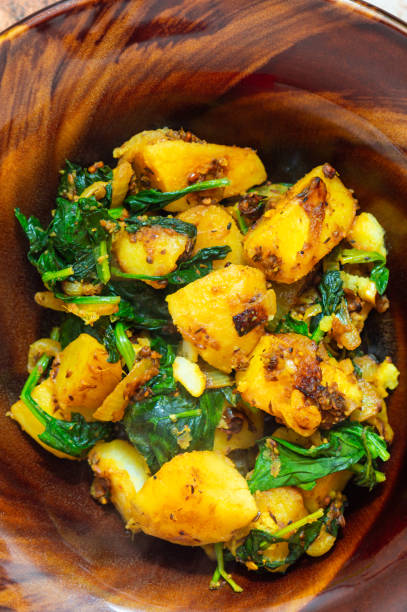 Indian saag aloo, potato and greens curry dish platet on brown bowl